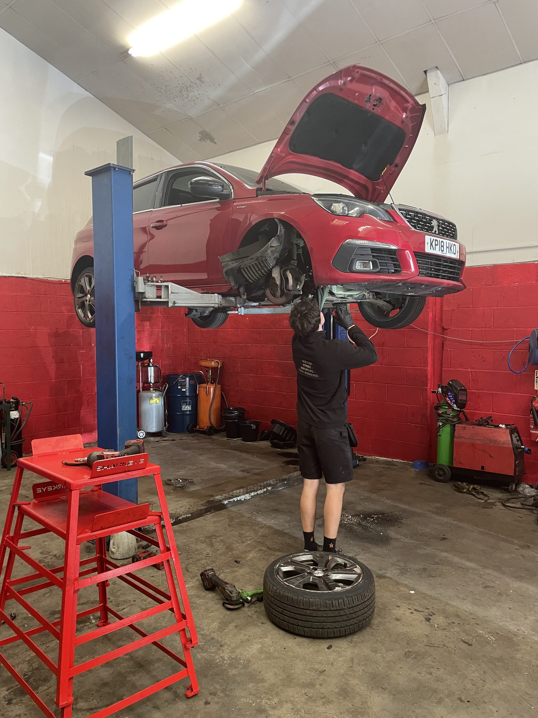 Mechanic working on a lifted red car